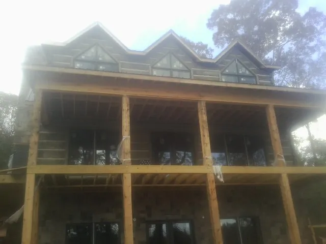 Dormers and porch framing on a large log home under construction — Roof Coating work by our crew in Grantville